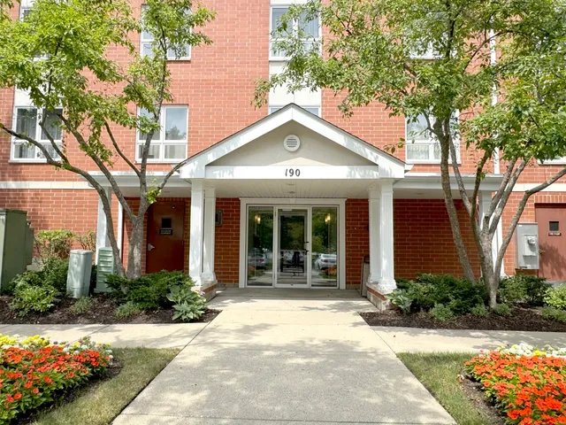 a view of a house with brick walls plants and large trees