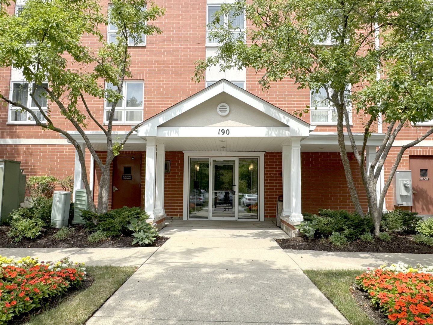 a view of a house with brick walls plants and large trees