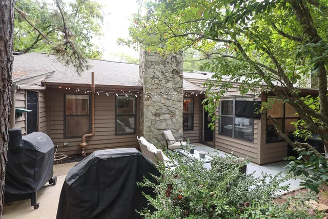 a backyard of a house with table and chairs and a large tree