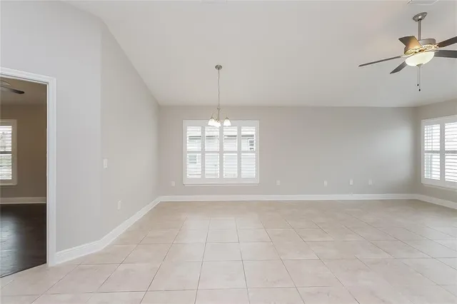 an empty room with windows and chandelier fan