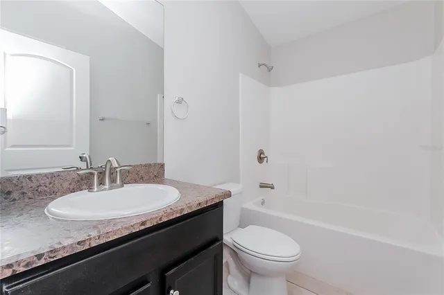 a bathroom with a granite countertop sink a toilet and a bathtub