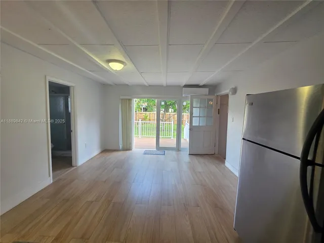 a view of empty room with wooden floor and window