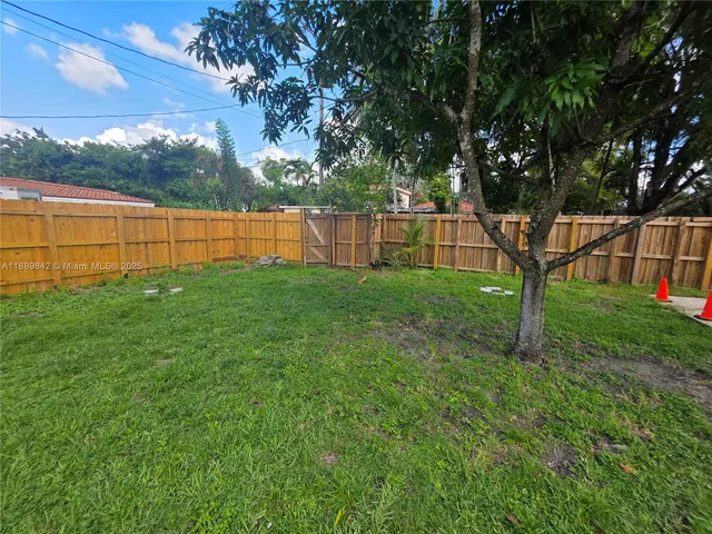 a view of a backyard with large trees and wooden fence