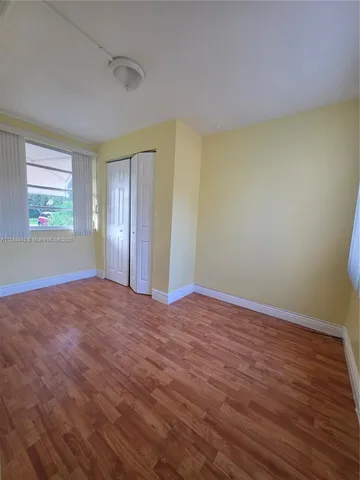 a view of an empty room with window and wooden floor