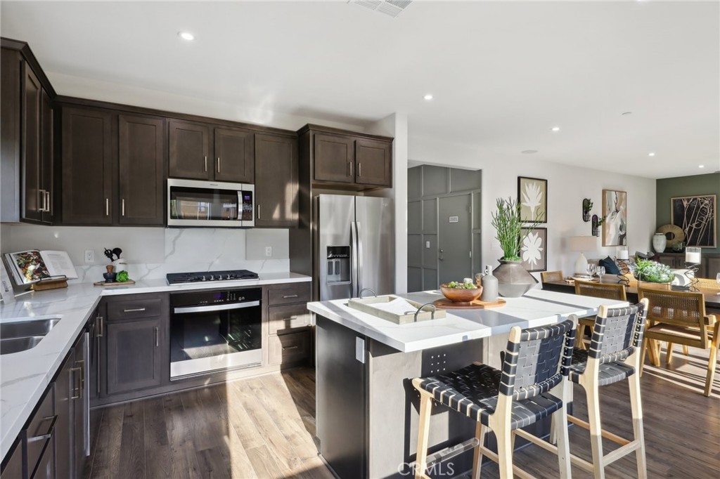 83241 Thrush Way Indio, CA 92201 - Photo 12 of 33 a kitchen with stainless steel appliances kitchen island granite countertop a stove top oven a sink a stove a dining table and chairs