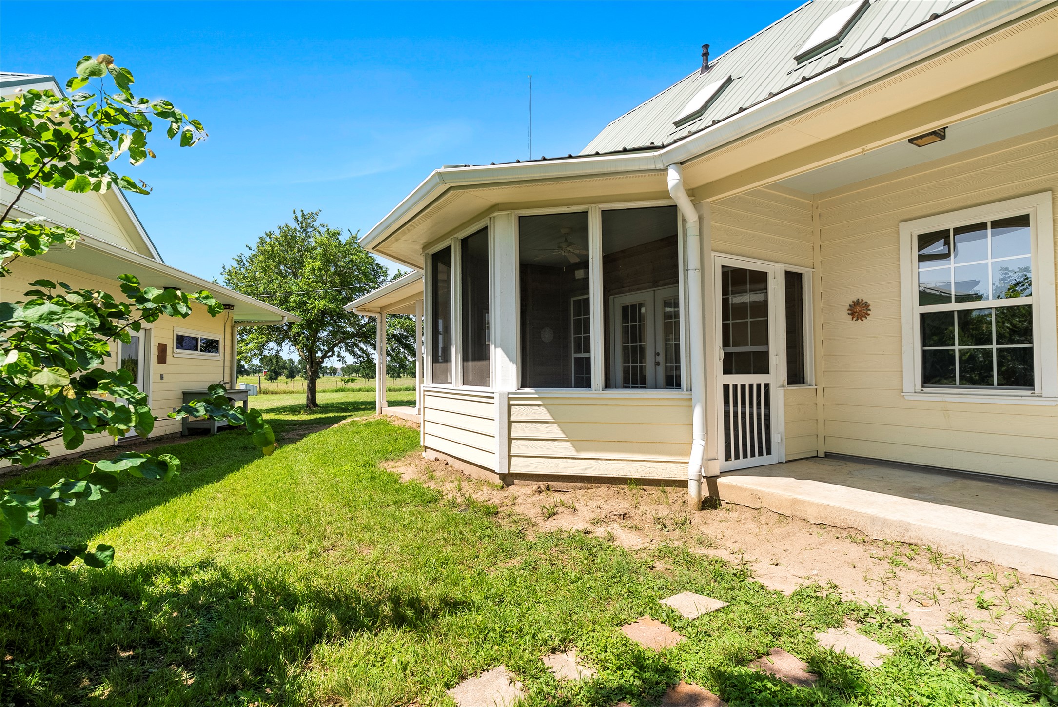 928 Upper Elgin River Road Elgin, TX 78621 - Photo 13 of 40 Yellow siding exterior with white trim, featuring a screened-in porch with French doors.
