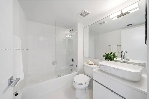 a bathroom with a bathtub shower sink mirror and toilet