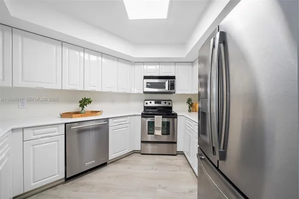a kitchen with white cabinets and stainless steel appliances