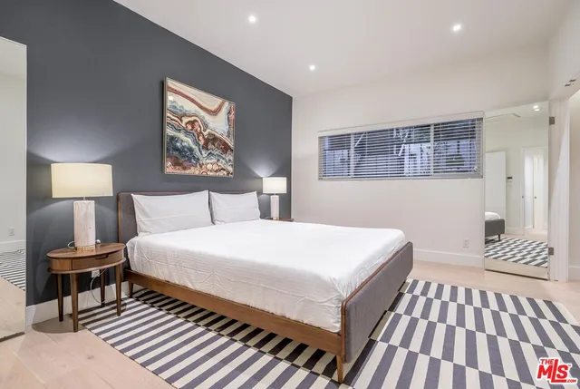 a bedroom with a large bed and a lamp on dresser