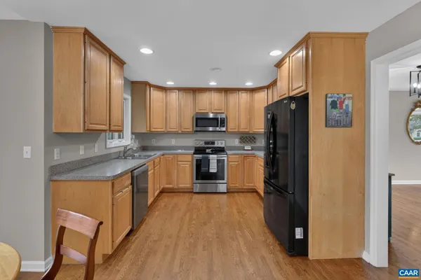 a kitchen with stainless steel appliances granite countertop a refrigerator a stove top oven a sink and dishwasher with wooden floor