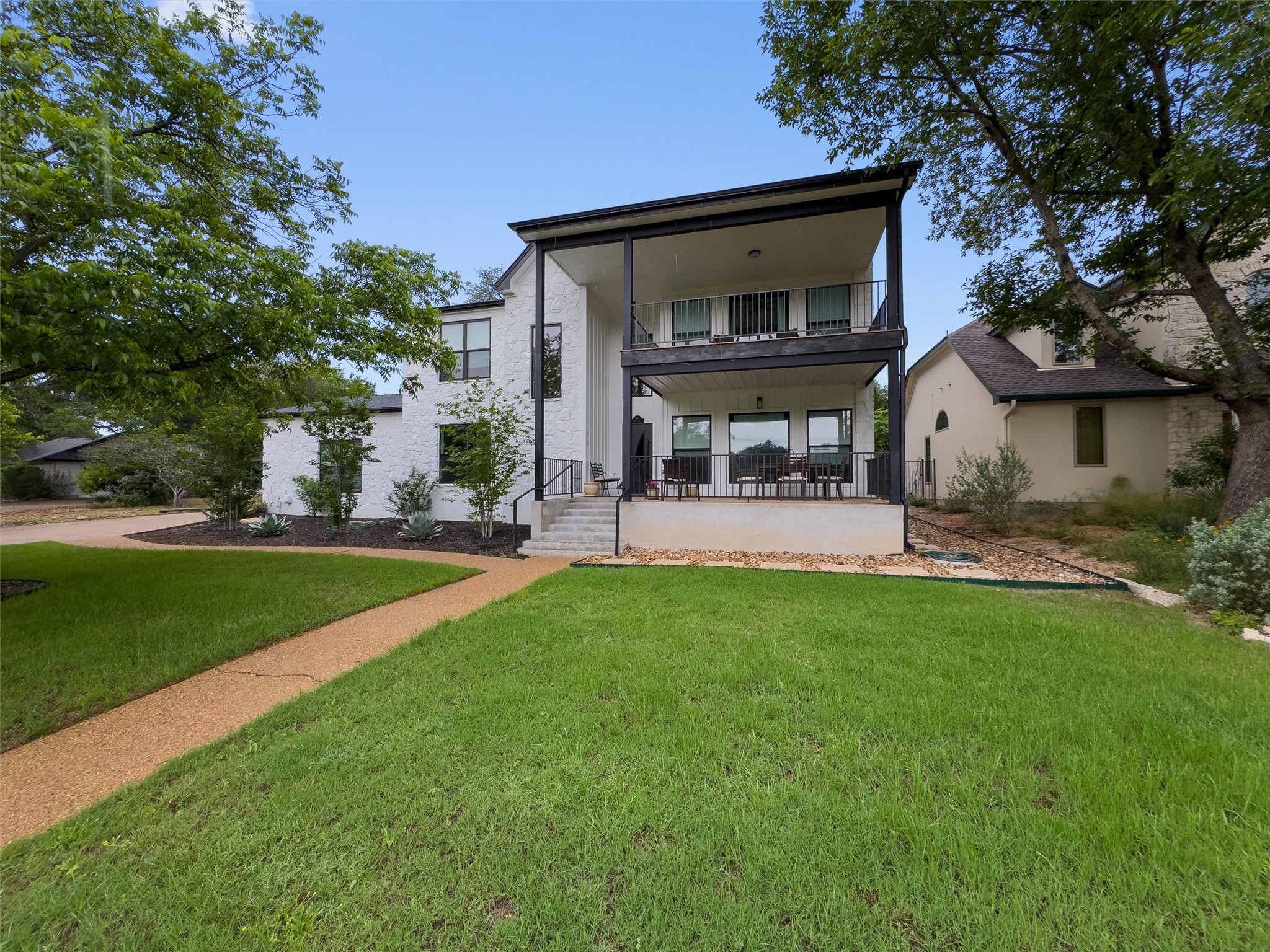307 Hurst Creek Road Austin, TX 78734 - Photo 3 of 40 Contemporary multi-level residence featuring a double balcony, white stucco exterior, and black trim accents
