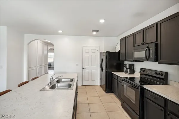 a kitchen with stainless steel appliances kitchen island granite countertop a refrigerator and a sink