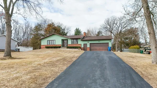 a front view of house with yard and trees in the background