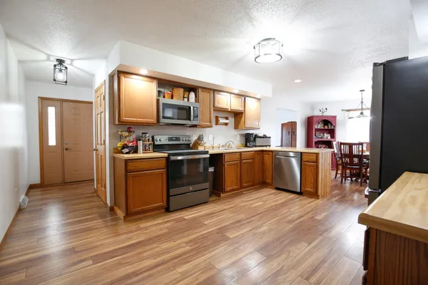 a kitchen with stainless steel appliances granite countertop a refrigerator a stove and a wooden floors