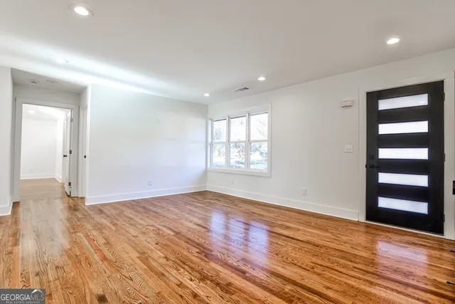 a view of an empty room with wooden floor and a window