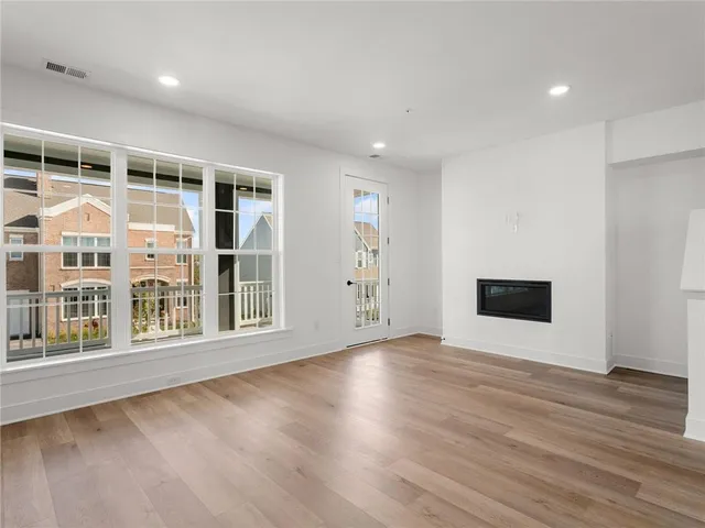 a view of an empty room with wooden floor and windows