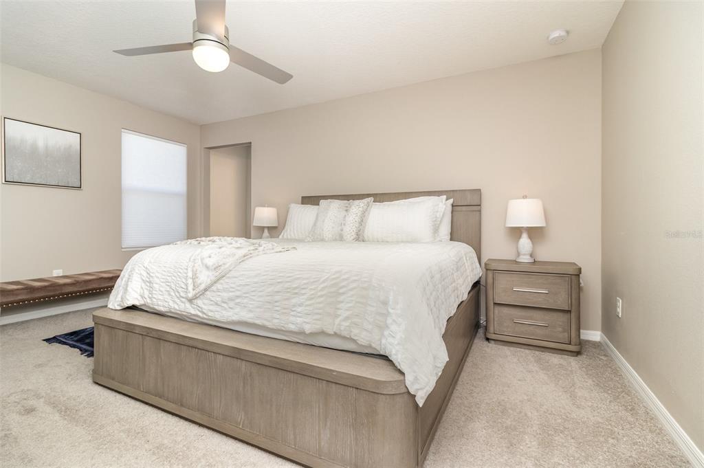 2461 Avian Loop Kissimmee, FL 34741 - Photo 15 of 36 a large bed sitting in a bedroom next to a window and a chandelier