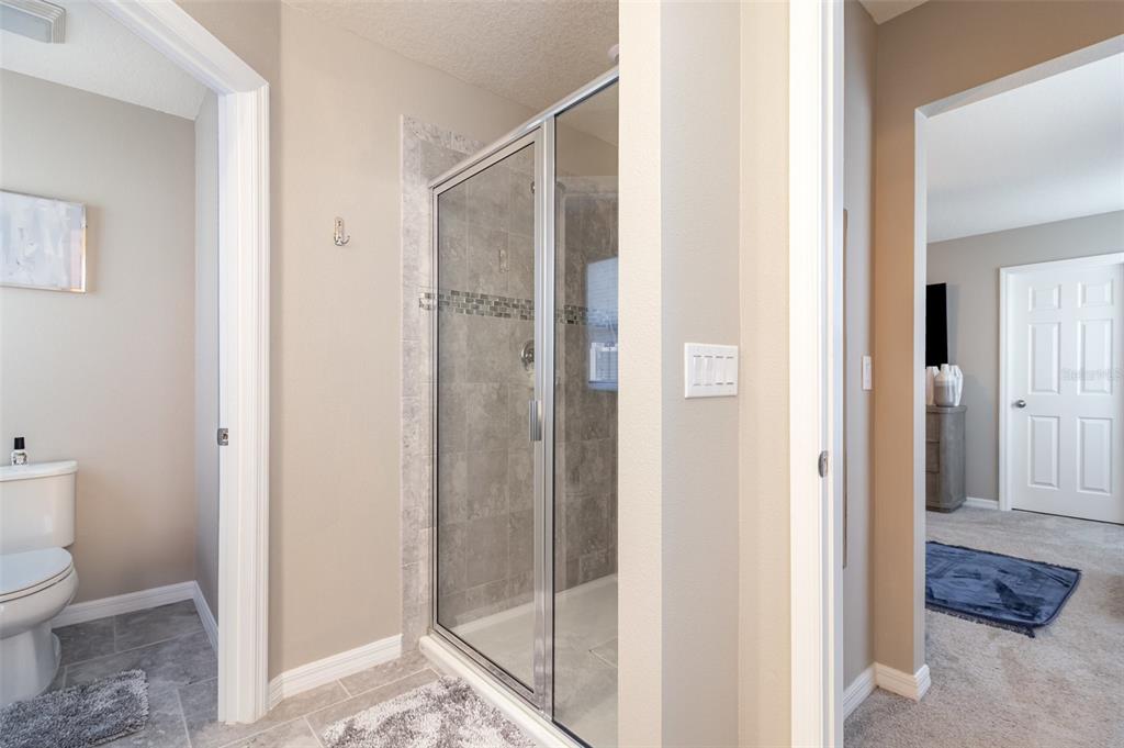 2461 Avian Loop Kissimmee, FL 34741 - Photo 18 of 36 a bathroom with a glass shower door