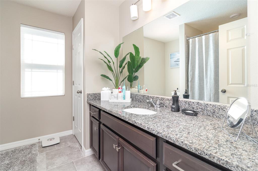 2461 Avian Loop Kissimmee, FL 34741 - Photo 23 of 36 a bathroom with a granite countertop sink and a mirror