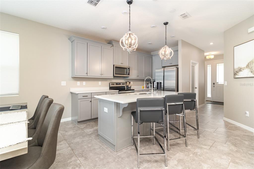 2461 Avian Loop Kissimmee, FL 34741 - Photo 10 of 36 a kitchen with a dining table a sink cabinets and stainless steel appliances