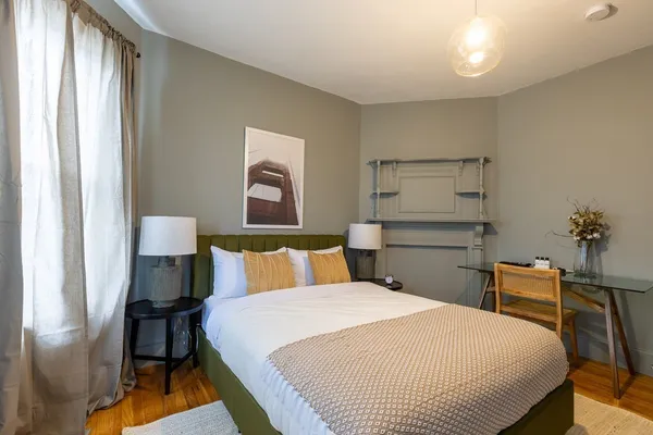 a bedroom with a bed and a lamp on dresser