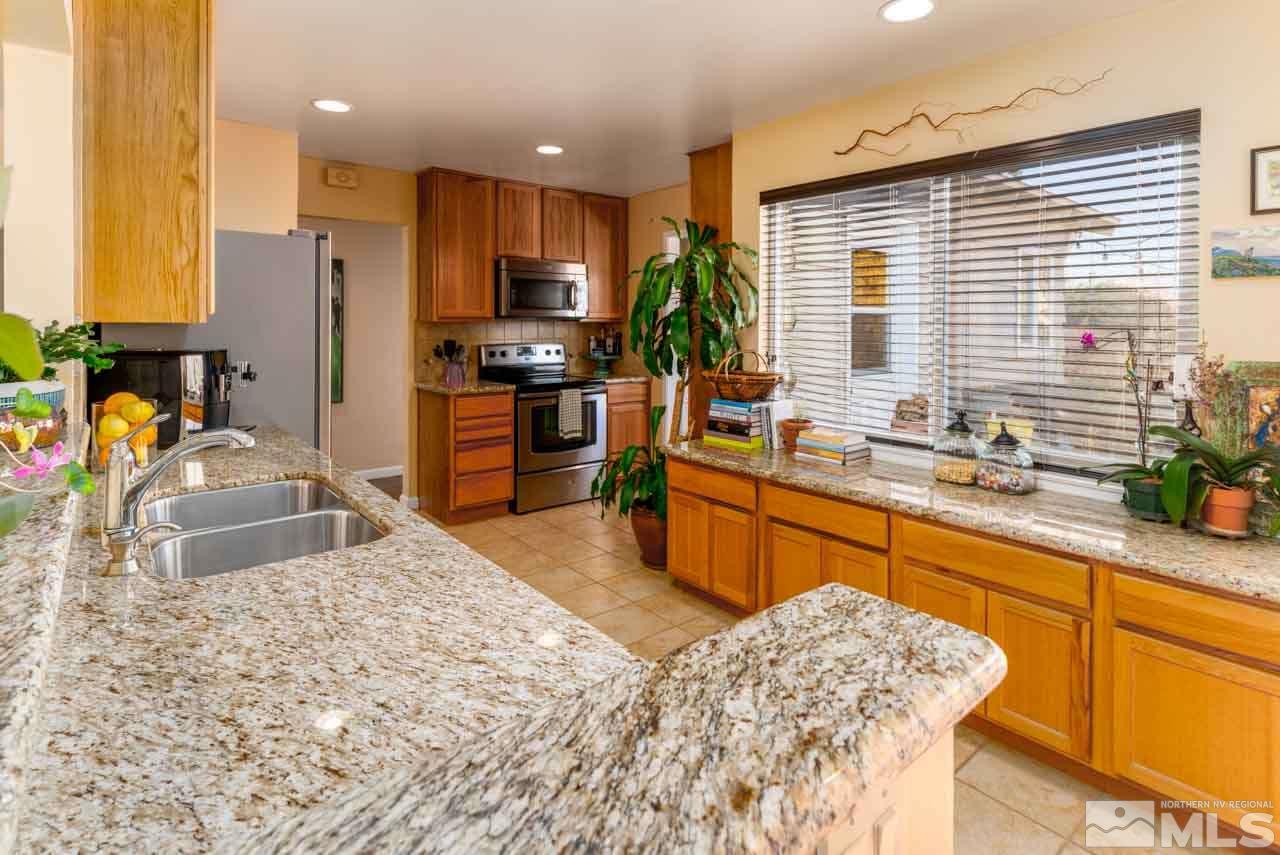655 Amber Circle Reno, NV 89509 - Photo 8 of 31 a kitchen with stainless steel appliances kitchen island granite countertop a sink refrigerator stove and microwave