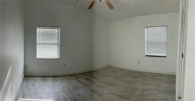 an empty room with wooden floor cabinet and windows