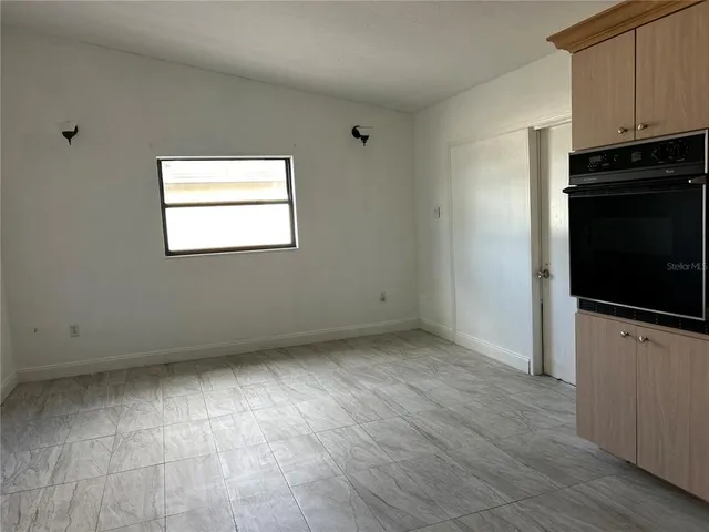 a view of an empty room with a kitchen and a window