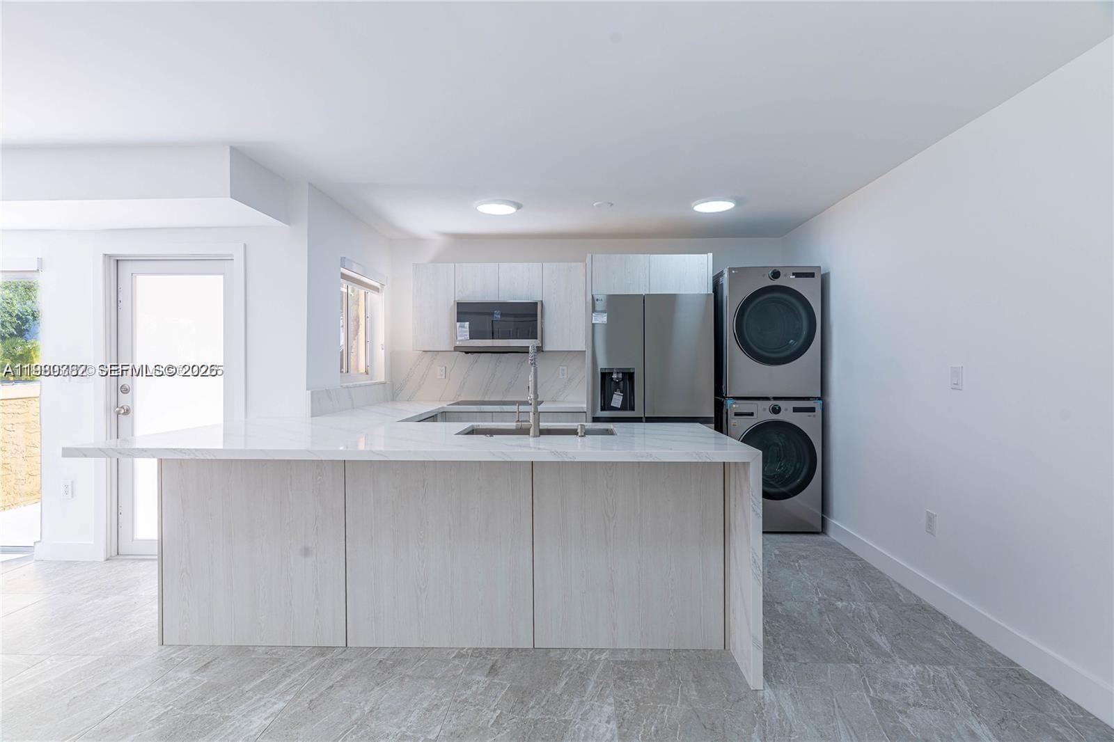 a view of kitchen with stainless steel appliances granite countertop cabinets and window