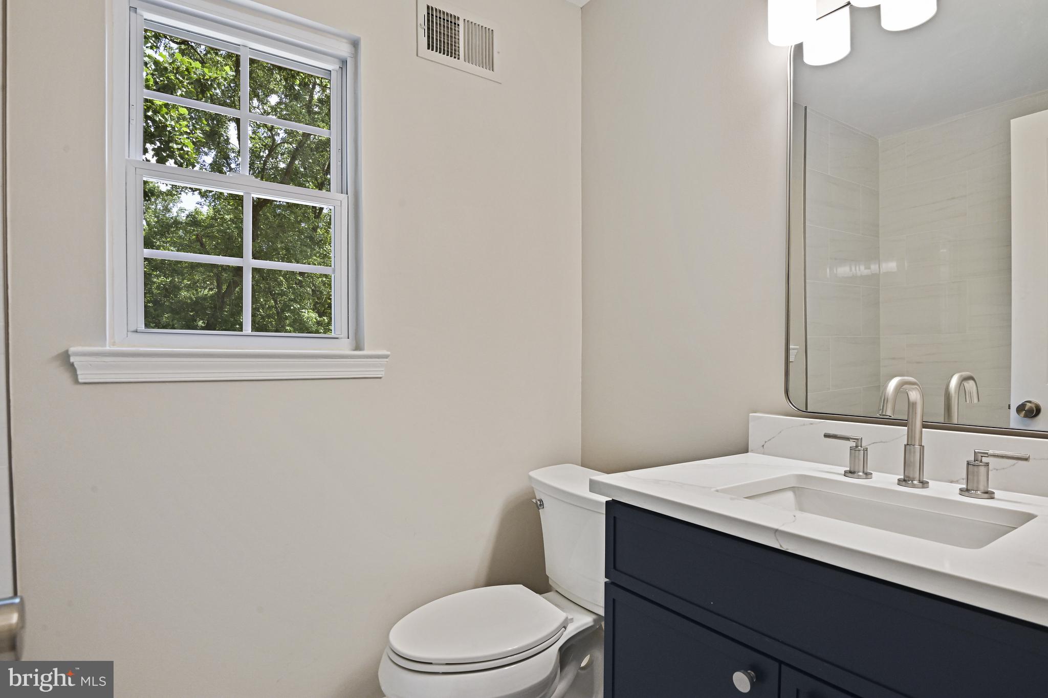 9060 Brook Ford Road Burke, VA 22015 - Photo 37 of 56 a bathroom with a granite countertop toilet a sink a mirror and a window