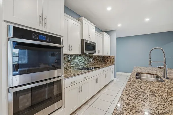 a kitchen with stainless steel appliances granite countertop a table chairs sink refrigerator and cabinets