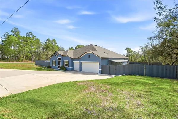 a view of a house with a big yard and large trees