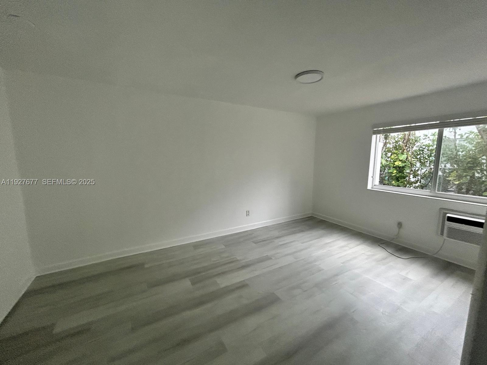 7430 Carlyle Avenue, Unit 2 Miami Beach, FL 33141 - Photo 5 of 8 an empty room with wooden floor and windows