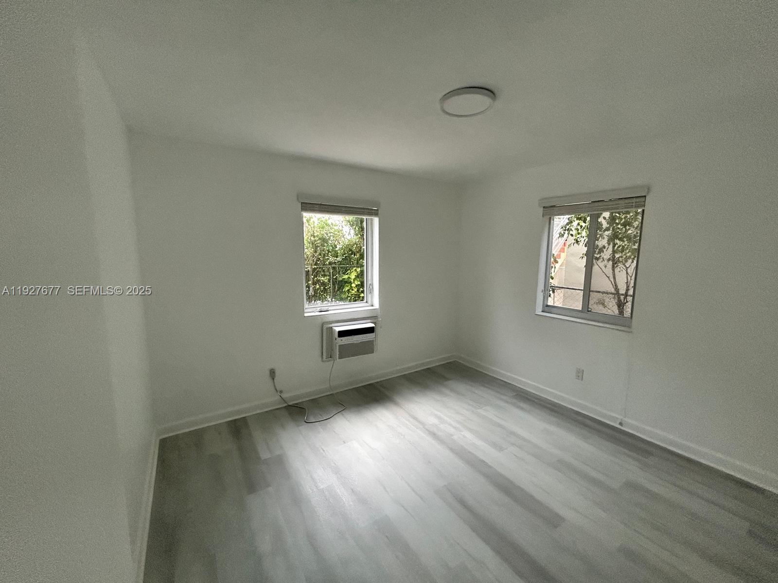 7430 Carlyle Avenue, Unit 2 Miami Beach, FL 33141 - Photo 7 of 8 an empty room with wooden floor and windows