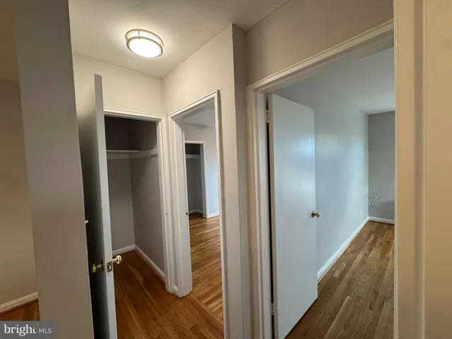 a view of hallway with stainless steel appliances wooden floor and closet