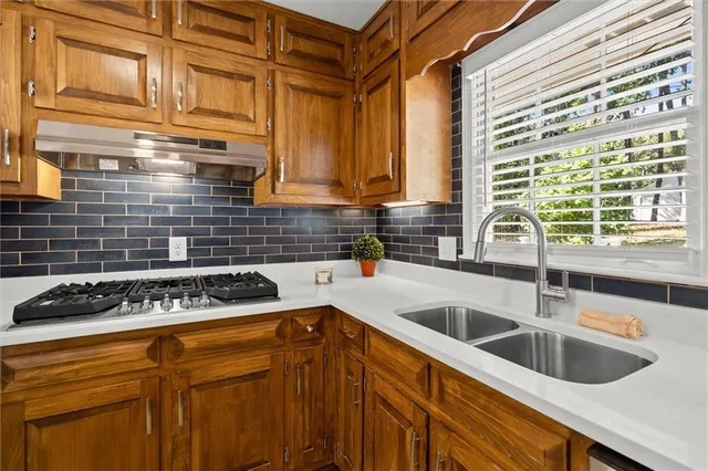 a kitchen with stainless steel appliances a sink a stove and cabinets