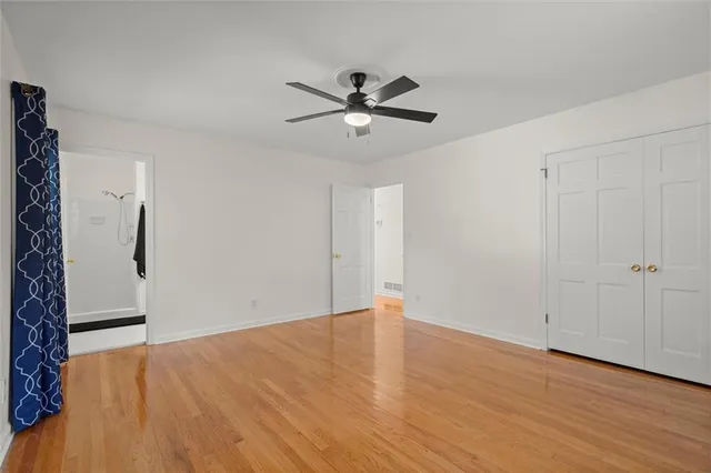 a view of an empty room with wooden floor and a ceiling fan