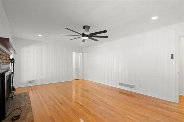 an empty room with wooden floor and a ceiling fan