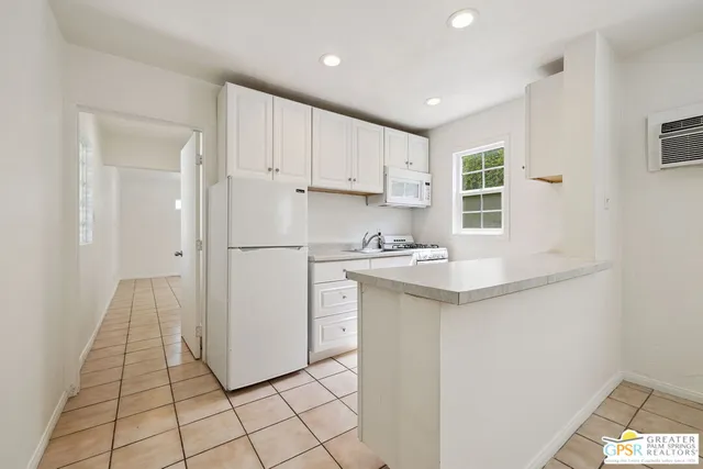 a kitchen with a sink a refrigerator a window and cabinets