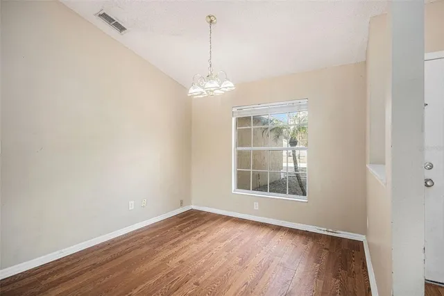 an empty room with wooden floor cabinet and windows