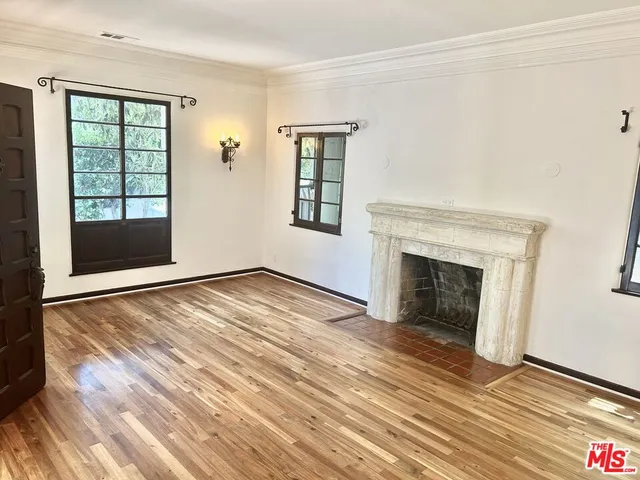 wooden floor fireplace and windows in an empty room