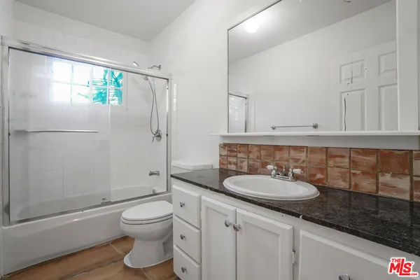 a bathroom with a granite countertop toilet sink and mirror