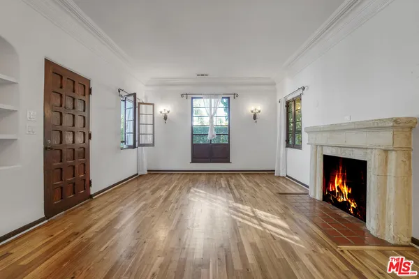 a view of an empty room with wooden floor fireplace and a window