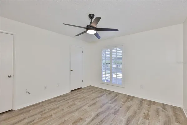 a view of empty room with wooden floor and fan
