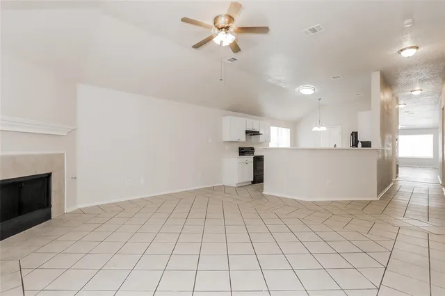 a view of empty room with kitchen view and a fireplace