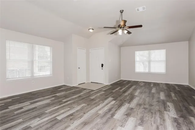 an empty room with windows and fan