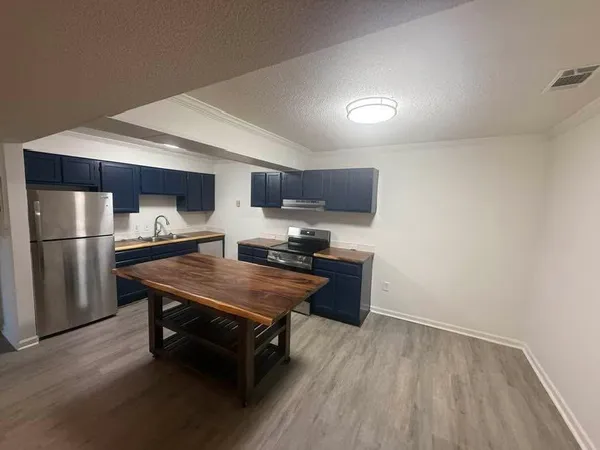 a kitchen with stainless steel appliances granite countertop a refrigerator a sink dishwasher a stove with wooden cabinets and floors