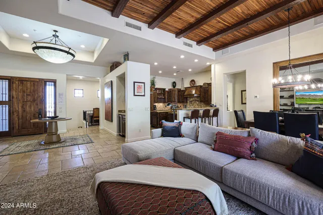 a living room with furniture kitchen view and a chandelier