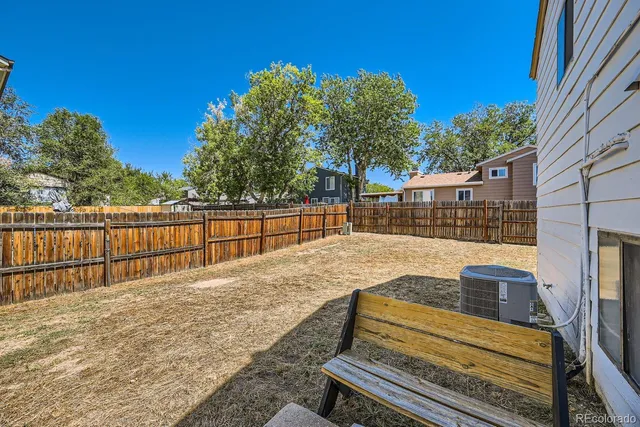 a view of backyard with wooden fence and trees