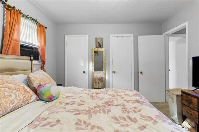 a bedroom with a bed and a flat tv screen on dresser